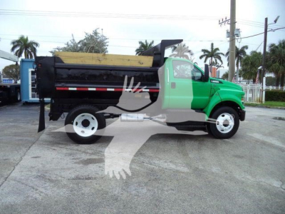 Truck side view showing green cab and black dump bed with white wheels.