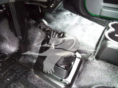 Shift lever area inside Ford F650 SD cab showing gear selector boot and surrounding floor with textured rubber mat and cup holders.