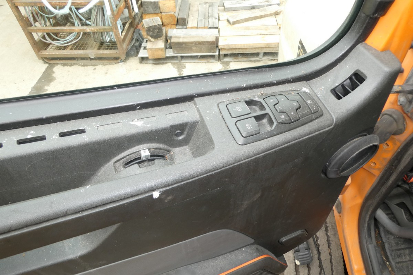 Volvo VNR64T300 truck interior door panel view with window controls and rugged surface in cabin.