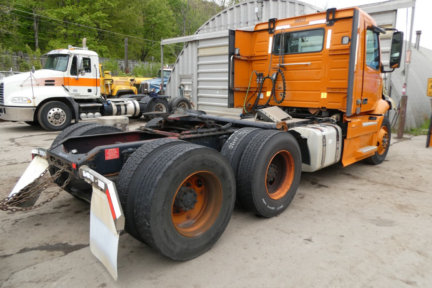 Volvo VNR64T300 truck chassis showing rear view with dual rear axles, orange cab, and exposed fifth-wheel connection.