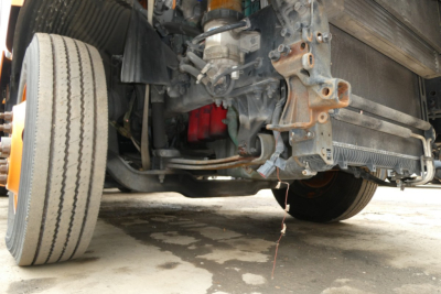 Front undercarriage of a Volvo VNR truck showing front suspension, left front tire, chassis, and radiator area.
