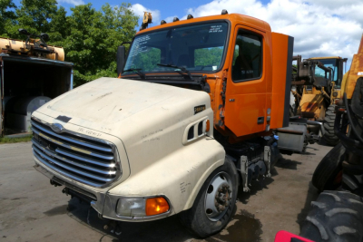 Volvo VNR64T300 truck cab in front of orange sleeper and white front bumper, indicating a used conventional daycab tractor with visible front grille and wheel.