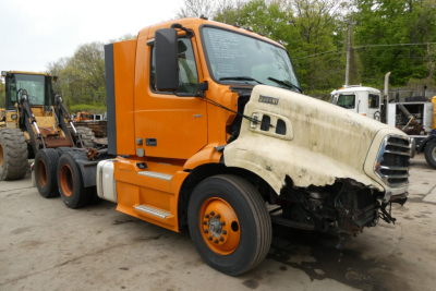 Volvo VNR64T300 truck damaged front bumper with cab in orange and white hood visible
