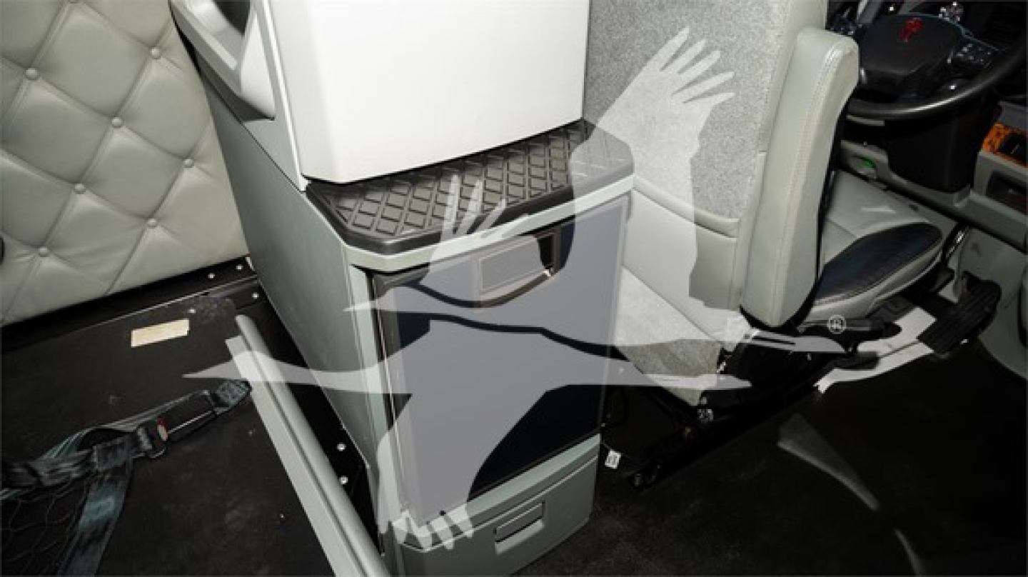 Cab interior showing center console area and steering wheel in a Kenworth T680 with light gray upholstery.
