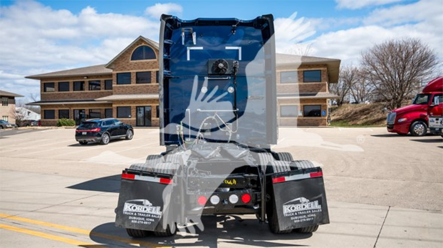 Rear view of a Kenworth truck tractor showing fifth-wheel and mudflaps with Kordell branding, blue trailer tilt, and surrounding dealership lot.