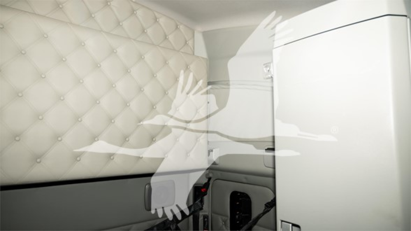 Kenworth T680 sleeper cab interior showing quilted upholstered side panel and a white cabinet with a handle.