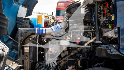 Kenworth T680 engine bay showing various hoses and components with blue intake hose and grey wiring in view