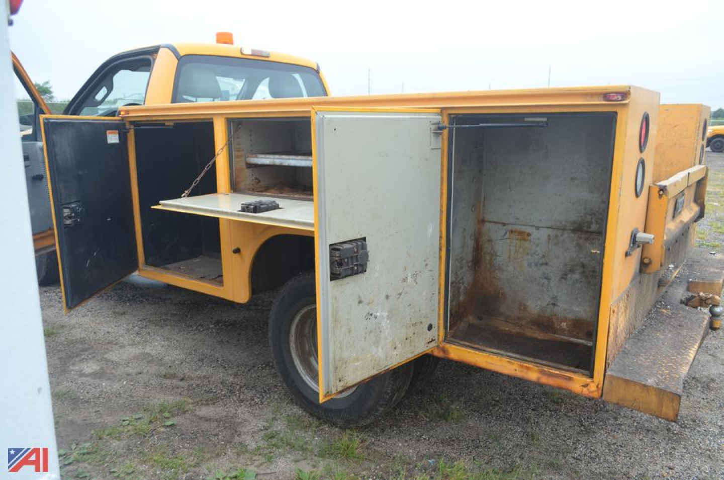 Ford F-350 utility body with open side compartments and rear plow equipment. Yellow body, multiple storage doors open showing metal shelves and interior.
