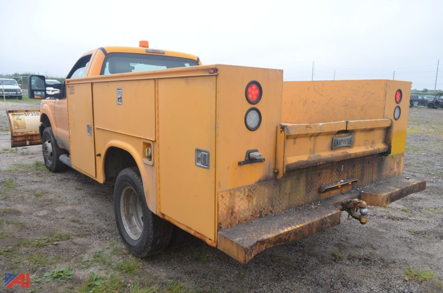 Utility body service truck with plow hitch showing rear cargo compartments and yellow body