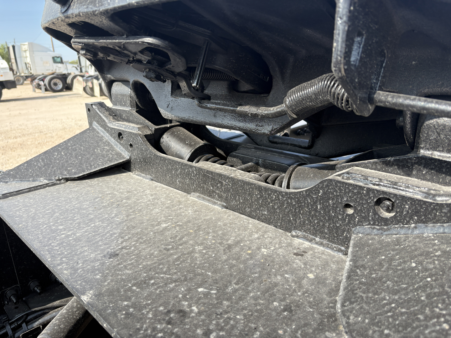 Truck cab area showing engine bay and structural components of a 2027 Mack GR64FT daycab, close view of frame and fascia with wiring harness and hydraulic lines.