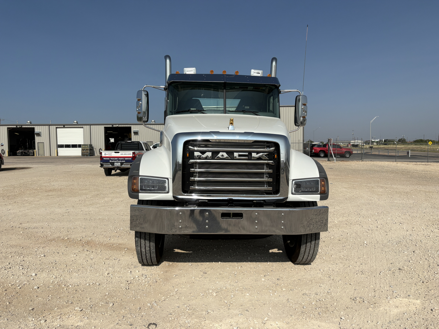 Front view of a new 2027 Mack GR64FT conventional daycab truck showing large chrome grille with MACK badge, bumper, headlights, and side mirrors.
