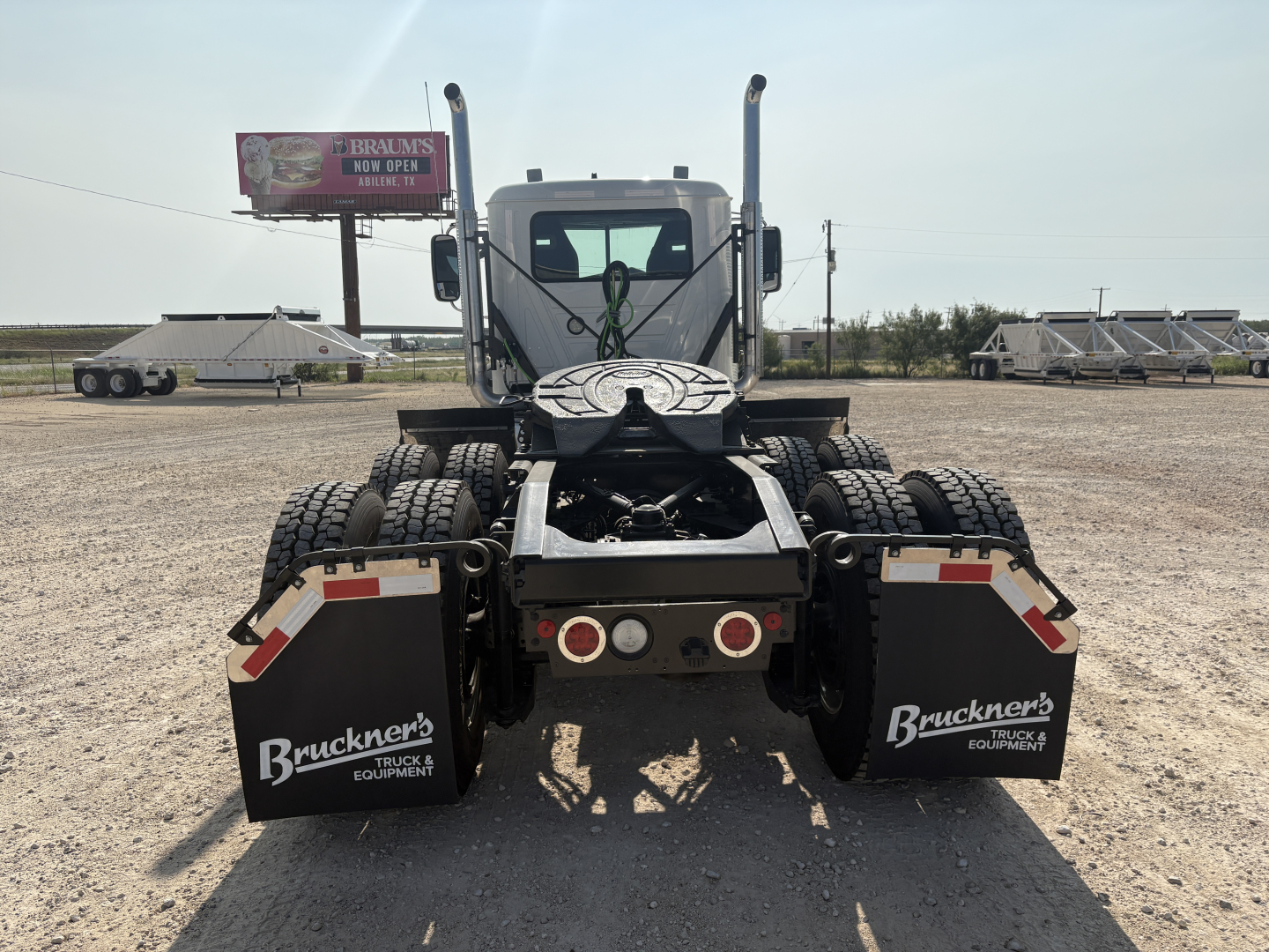 Truck rear view showing fifth wheel, dual rear axles, mud flaps with Brackner's Truck & Equipment logos, and two round taillights.