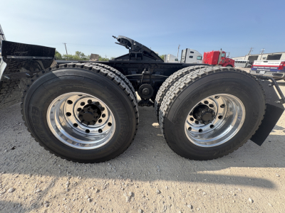 Dual rear axles of a Mack GR64FT chassis showing large chrome wheels and tires with black frame and suspension components.