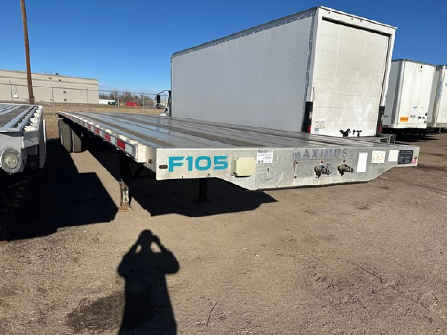 Flatbed trailer showing F105 graphic and front end with reflective tape and wheel axles visible.
