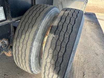 Dual tires on trailer showing tread with visible sidewalls and rusted rim area.