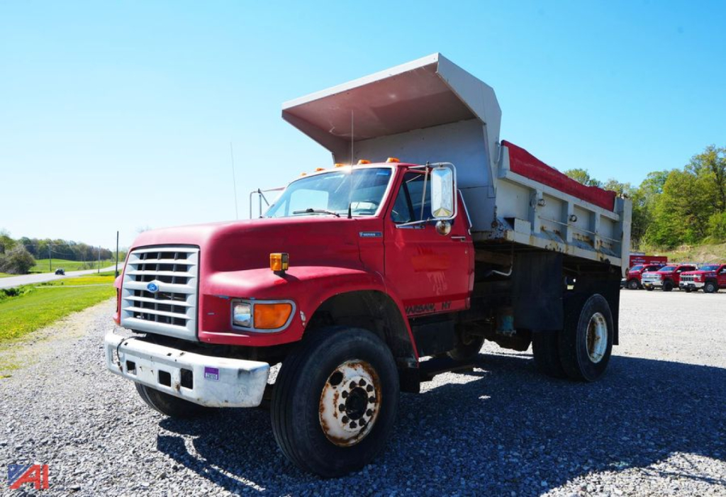 Ford F-80 dump truck in service showing red cab and large steel dump bed with white sides.