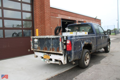 Ford F-250 Super Duty pickup truck with dump bed in a service facility lot showing rear and side view.