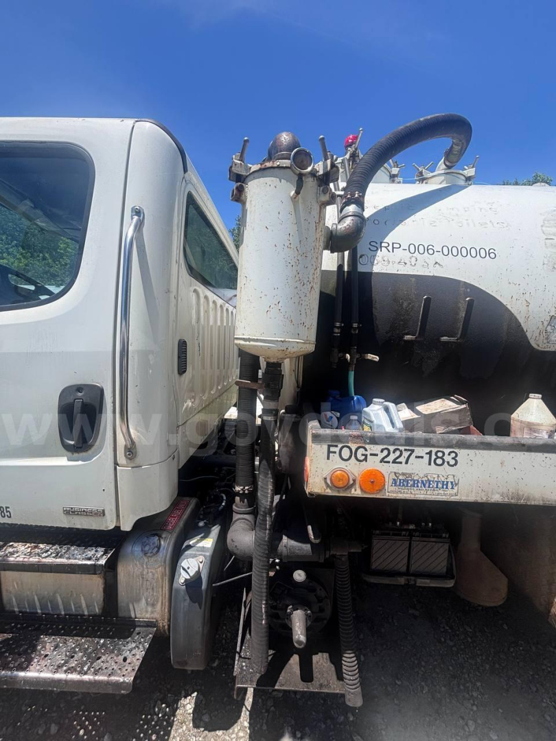 Truck chassis and cylindrical tank with hoses and hydraulic components, visible labels include FOG-227-183 on a metal bracket and SRP-006-000006 near the tank; front cab visible on left.