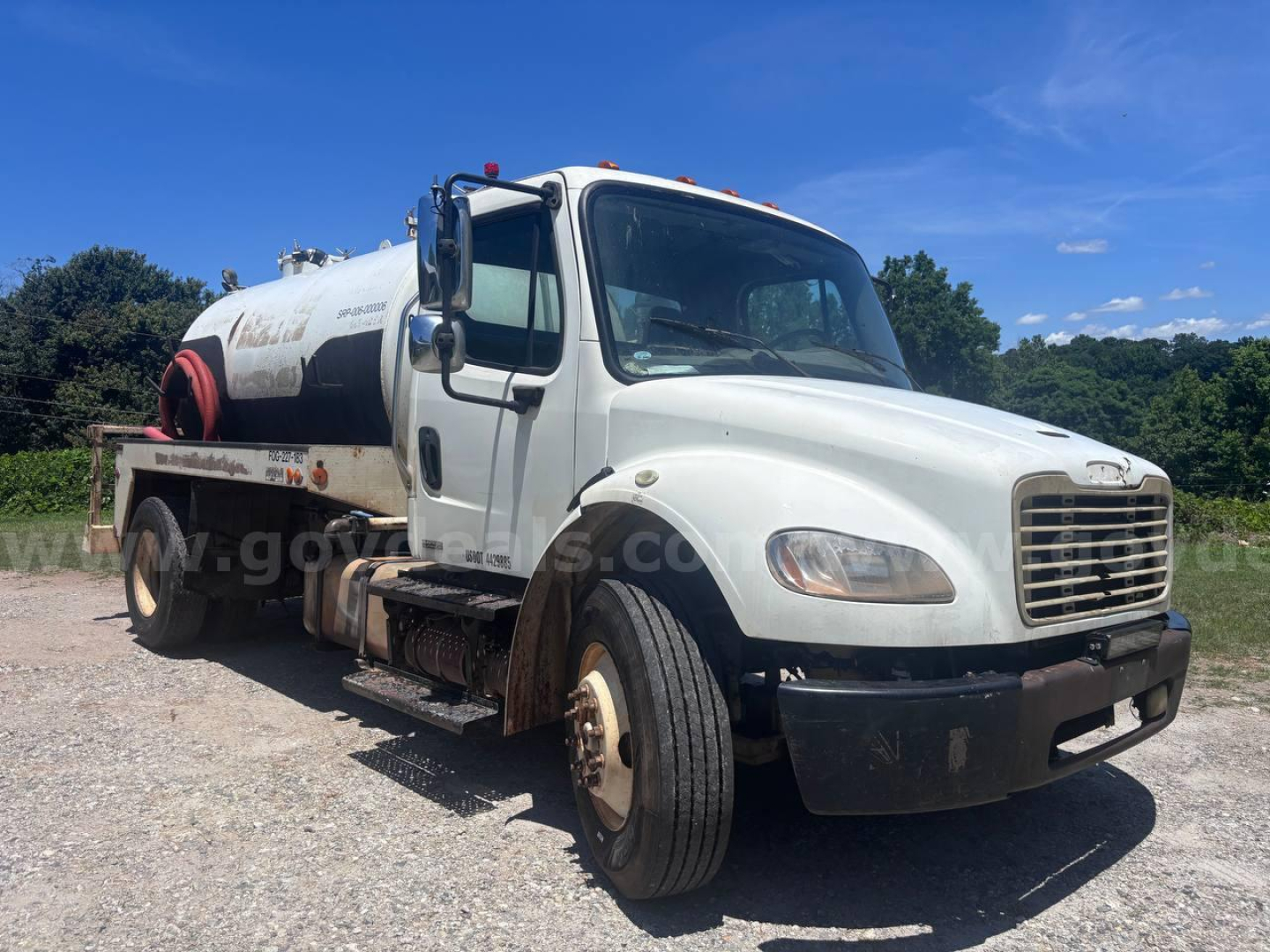 Vacuum truck cab and tank chassis showing Freightliner M2 106 with white cab and mounted cylindrical tank on a dual rear wheel chassis, VIN 1FVACWDT7CHBP3241 visible on listing page