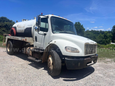 Freightliner M2 106 vacuum truck front-left view showing tank chassis and cab with white exterior and black bumper.