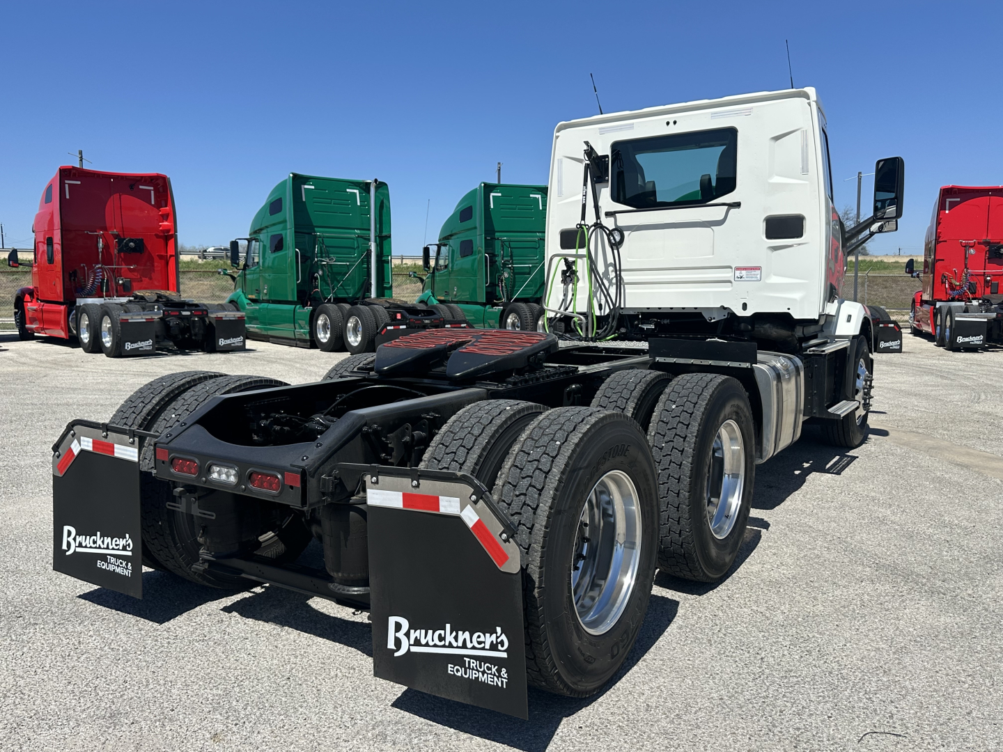 Truck chassis rear view showing dual rear axles and fifth wheel mounting with mud flaps and Bruckners equipment logos.