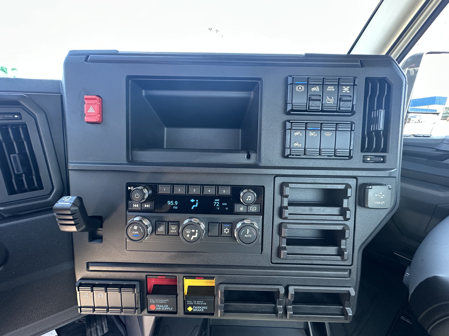 Dashboard of a 2027 Mack AN64T truck showing control panel with climate controls, storage compartments, and switch panels. Visible text includes various button labels but not fully legible.