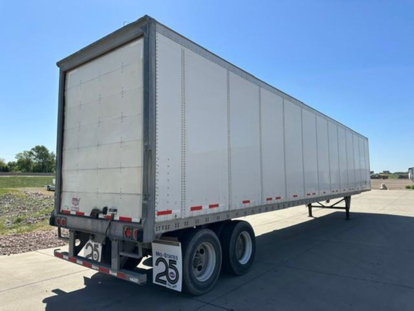 Trailer side and rear view of a 2016 Wabash van trailer showing tandem axles, gray exterior, rear doors, and stock number plate.