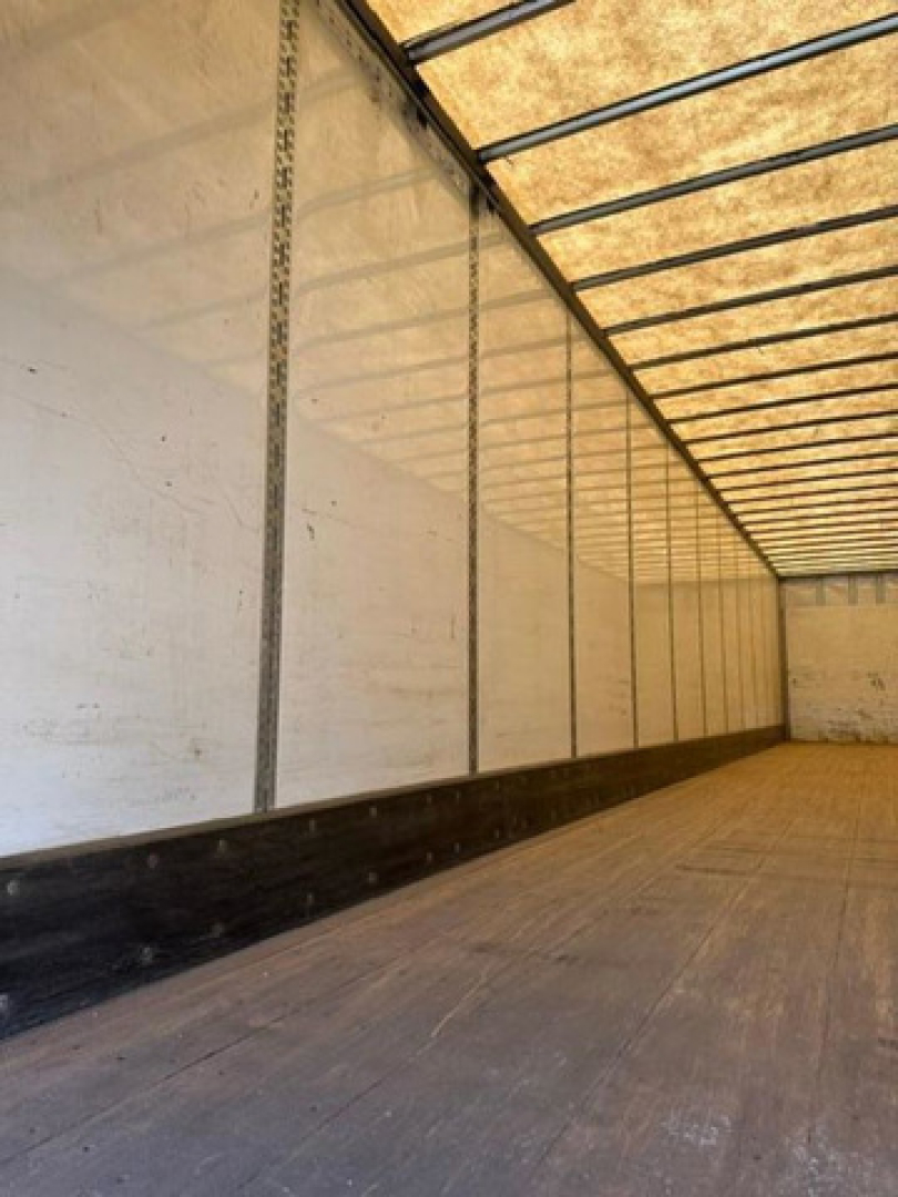 Trailer interior showing empty cargo area with vertical sidewall supports and wooden floor.