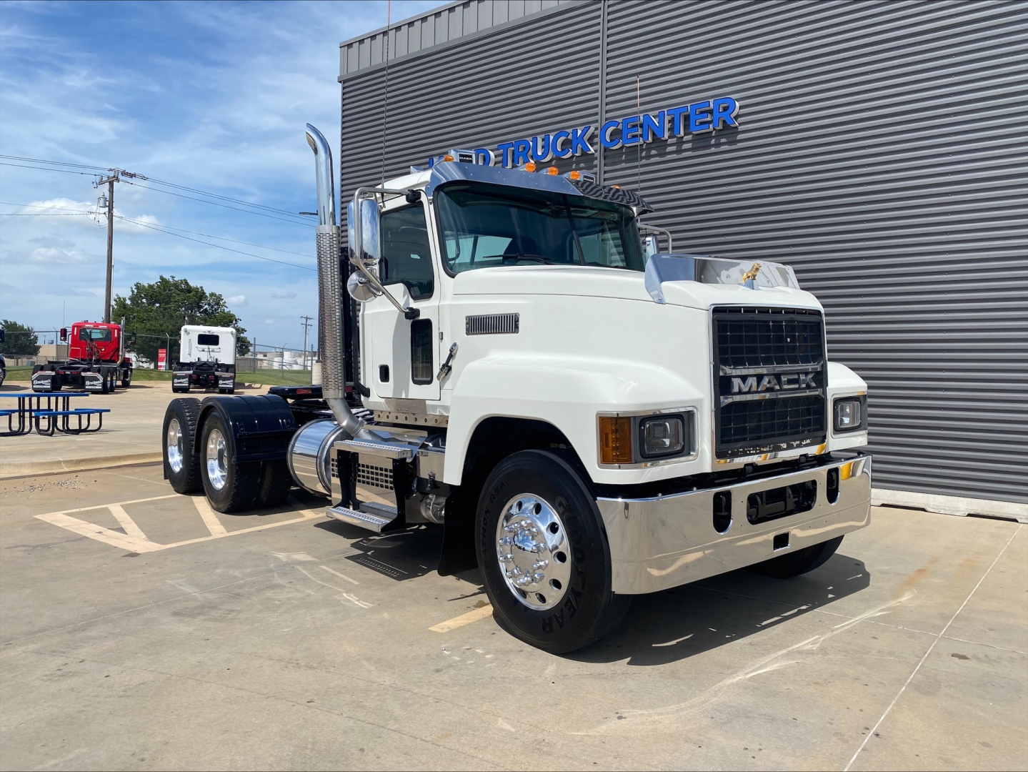 Mack PI64T conventional daycab truck in front of dealership showing white cab and chrome bumper.