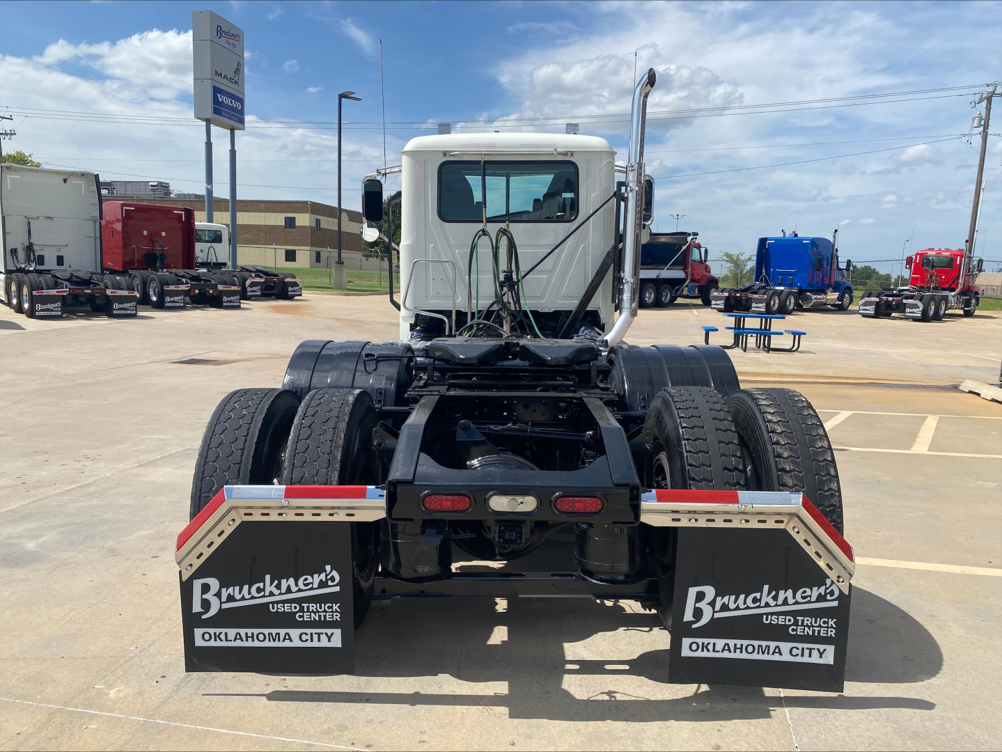 Rear view of a used 2021 Mack PI64T truck tractor showing dual rear axles and mud flaps with Bruckner’s Used Truck Center branding in Oklahoma City.