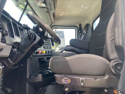 Cab interior of a Mack PI64T daycab showing driver seat and dashboard with steering wheel and controls.