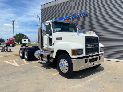 Mack PI64T conventional daycab truck in front of dealership showing white cab and chrome bumper.