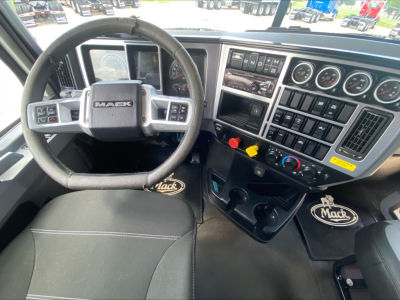Mack PI64T truck cab interior showing steering wheel with Mack logo, instrument cluster, and dashboard controls.