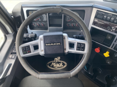Mack PI64T truck cockpit showing steering wheel with MAEK logo, dashboard gauges, and center console.