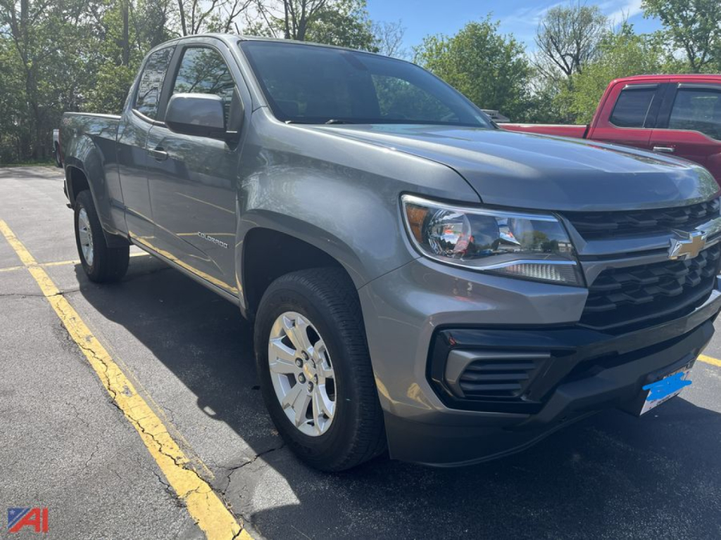 Chevrolet Colorado crew cab pickup truck in a parking lot, side/front view, silver with black grille, Chevrolet bowtie emblem on grille, alloy wheels, 4x4.