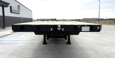 Flatbed trailer from rear showing deck and support legs, with hookup and markings along the bumper.