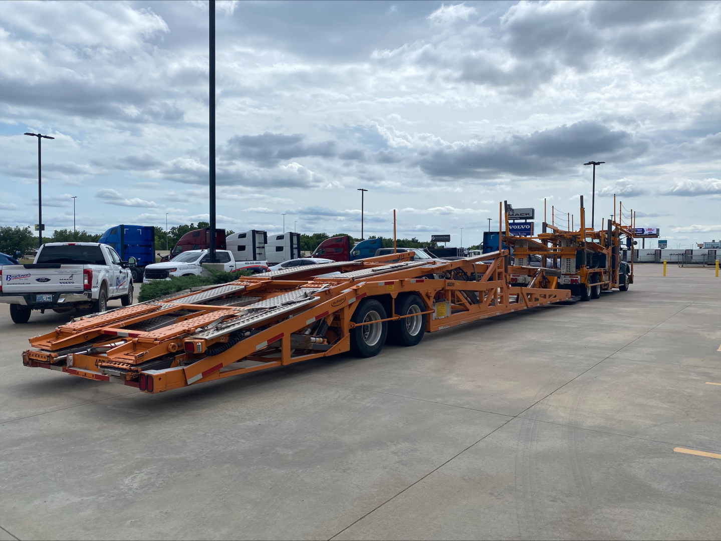 2014 Volvo VAH auto carrier trailer in a parking lot, orange lowboy with multiple axles and loading ramps.