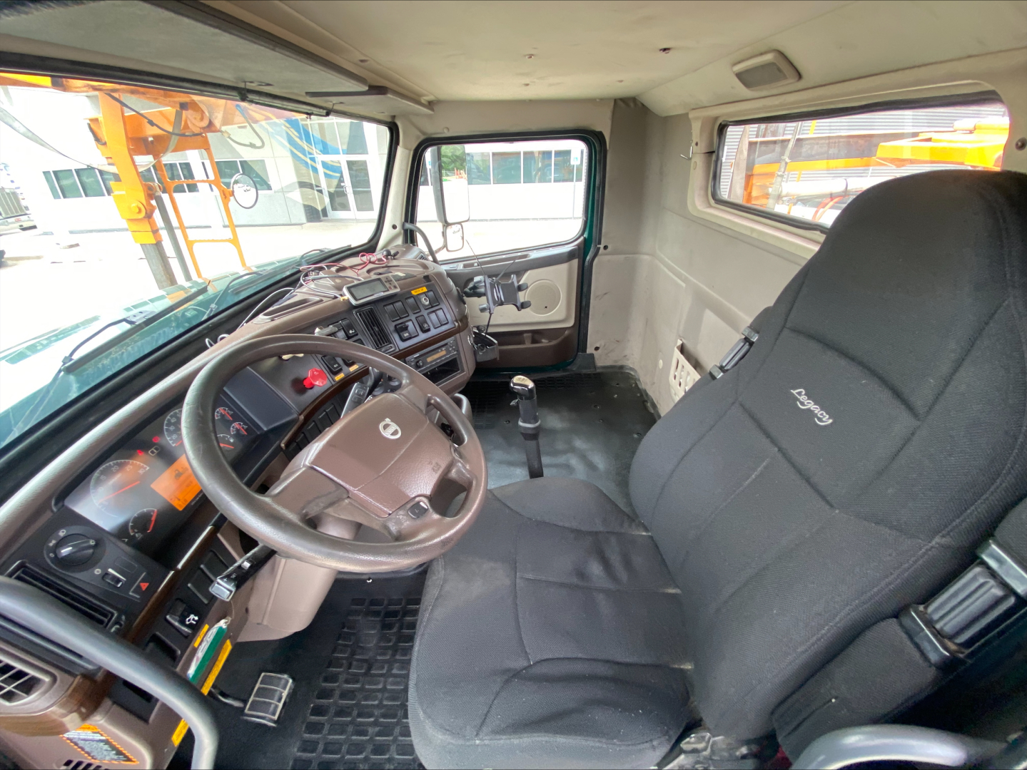 Truck cab interior showing steering wheel and driver seat in Volvo VAH, with dashboard and controls visible.