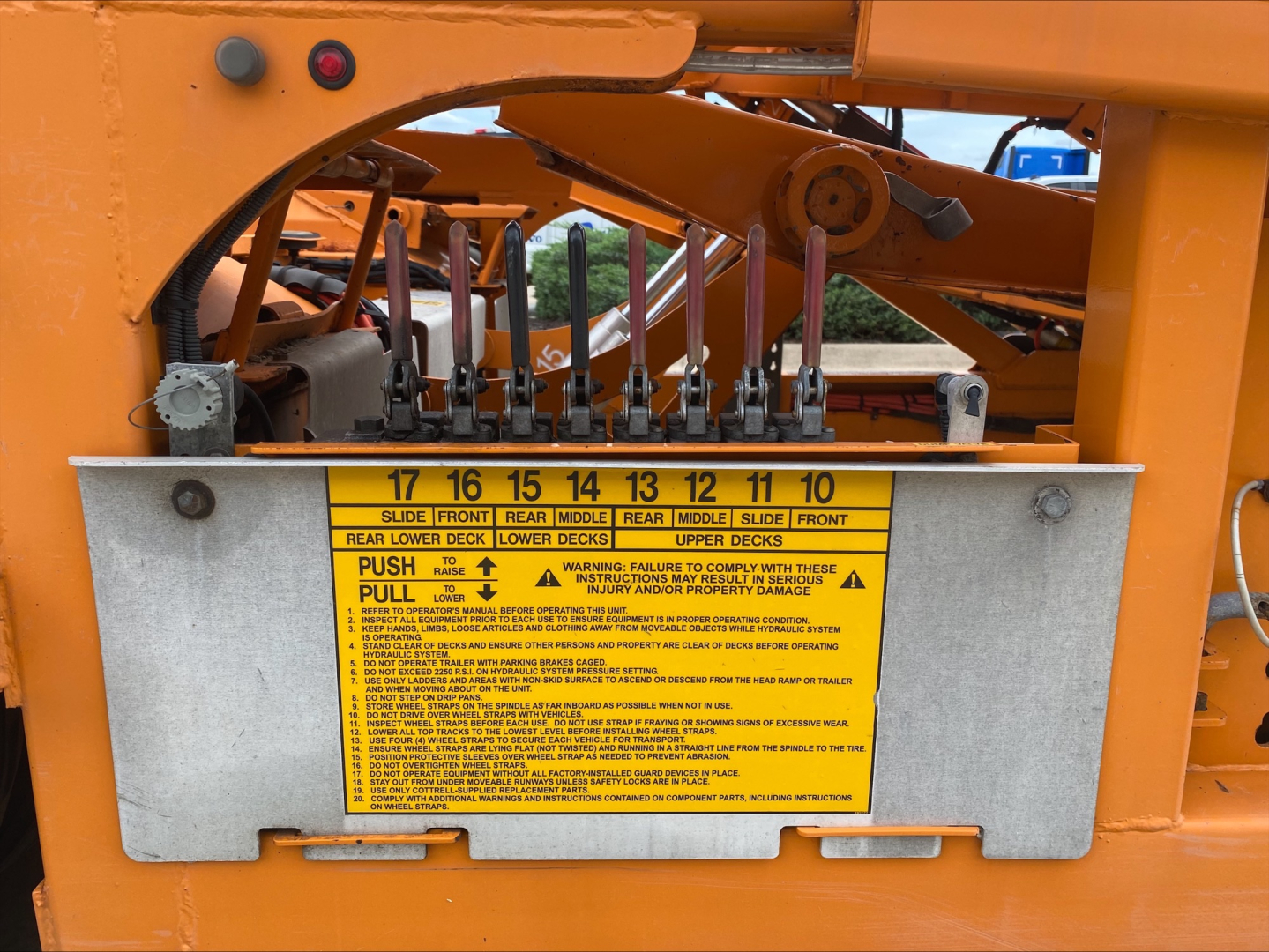 Control panel with numbered levers and a yellow safety label on an orange Volvo VAH auto carrier.