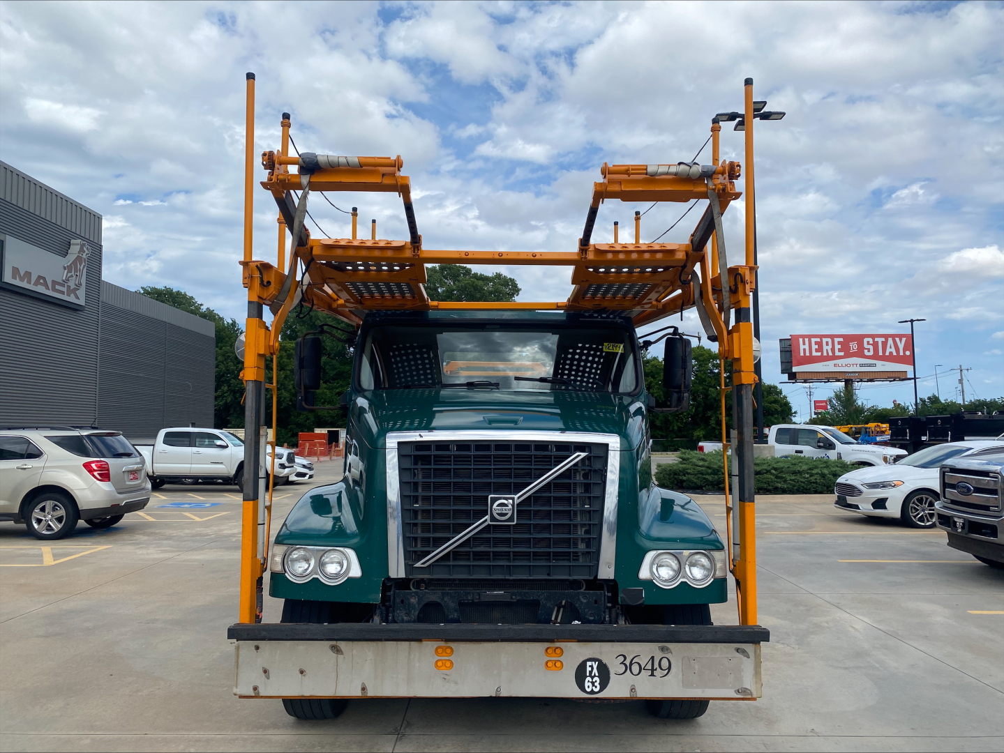 Volvo VAH truck front view showing car carrier frame and clearance bar equipment in yellow with green cab.