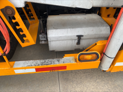 Alt text: Visual of a 2014 Volvo VAH auto carrier truck showing a silver fuel tank/mount undercarriage with orange safety rails and a small amber clearance light.