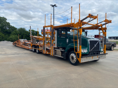 Volvo VAH auto carrier truck with green cab and orange car hauler frame, right-side view showing dual low-loader ramps and equipment.