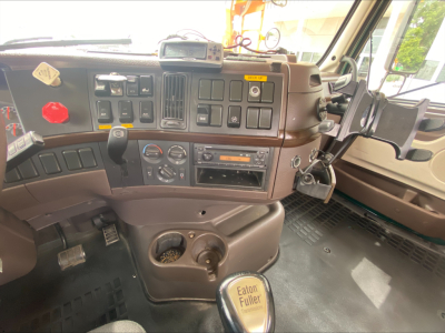 Cab interior of a Volvo VAH truck showing instrument panel, steering column, gear lever, air controls, and Eaton Fuller badge on shifter knob.