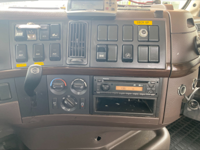 Dashboard of a Volvo VAH truck showing control switches, climate dials, radio, and compartments.