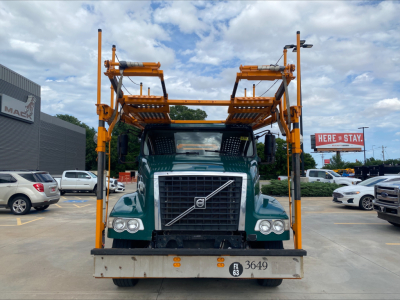 Volvo VAH truck front view showing car carrier frame and clearance bar equipment in yellow with green cab.