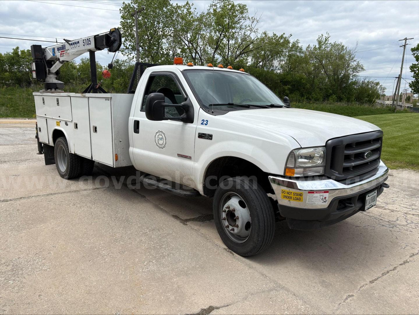 2004 Ford F450 service truck with utility bed and crane, in-service, side view showing utility compartments and crane equipment.