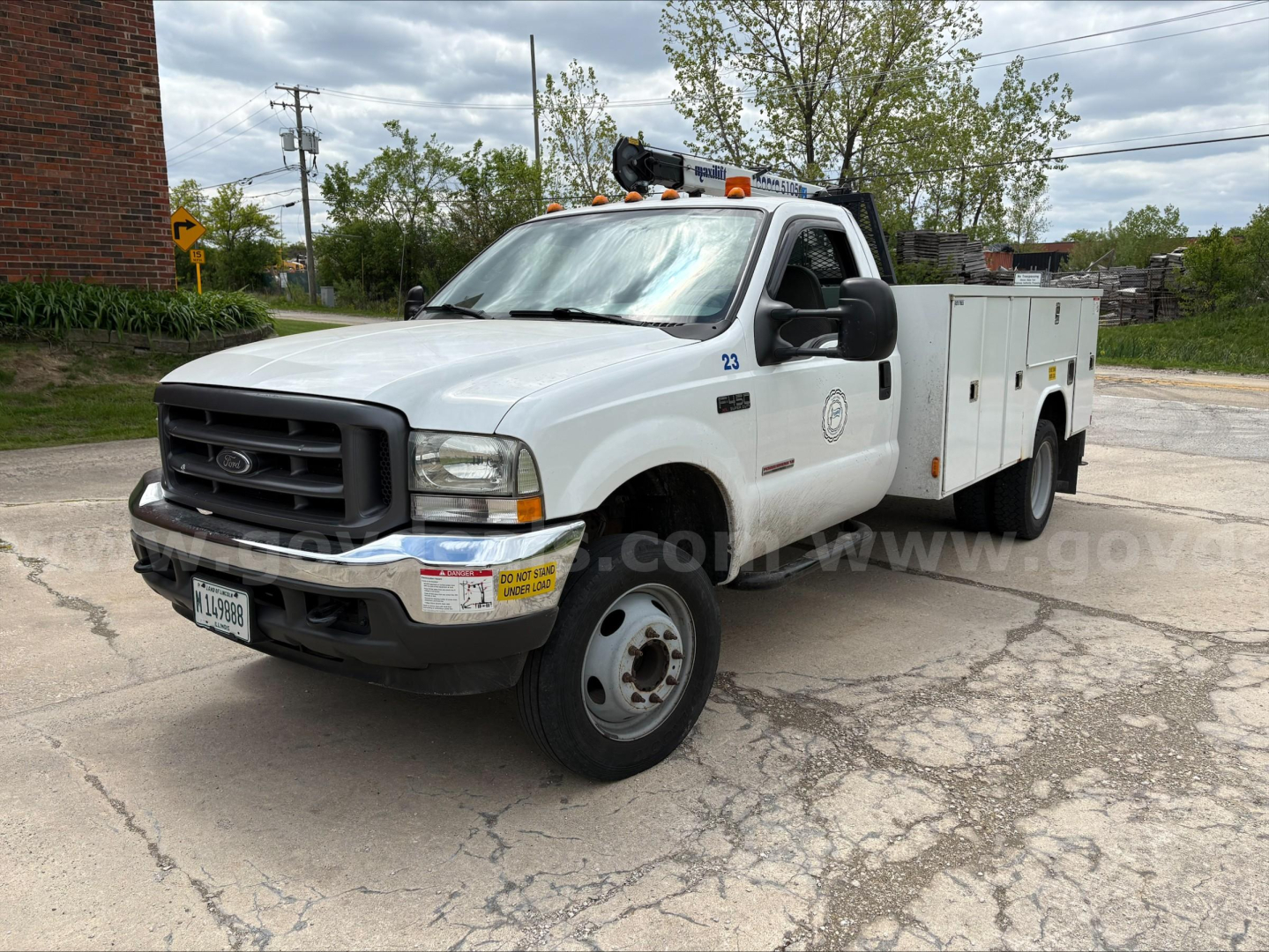 Ford F-450 utility service truck, white, crew cab with service utility bed panels, DOT lights on roof, front grille, bumper, and VIN plate visible.