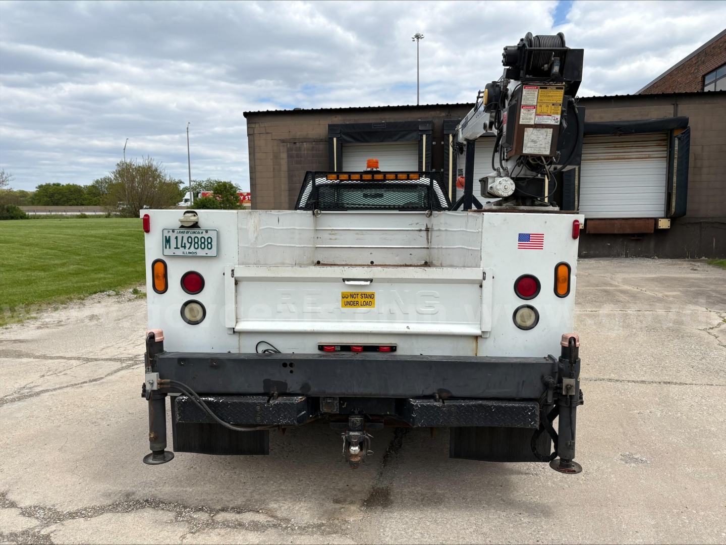 Ford F-450 service truck rear view with crane, utility bed, tailgate, license plate M14988, and warning decals.