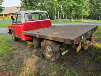 1968 Chevrolet C30 pickup truck with red cab and flatbed viewed from rear-left side.