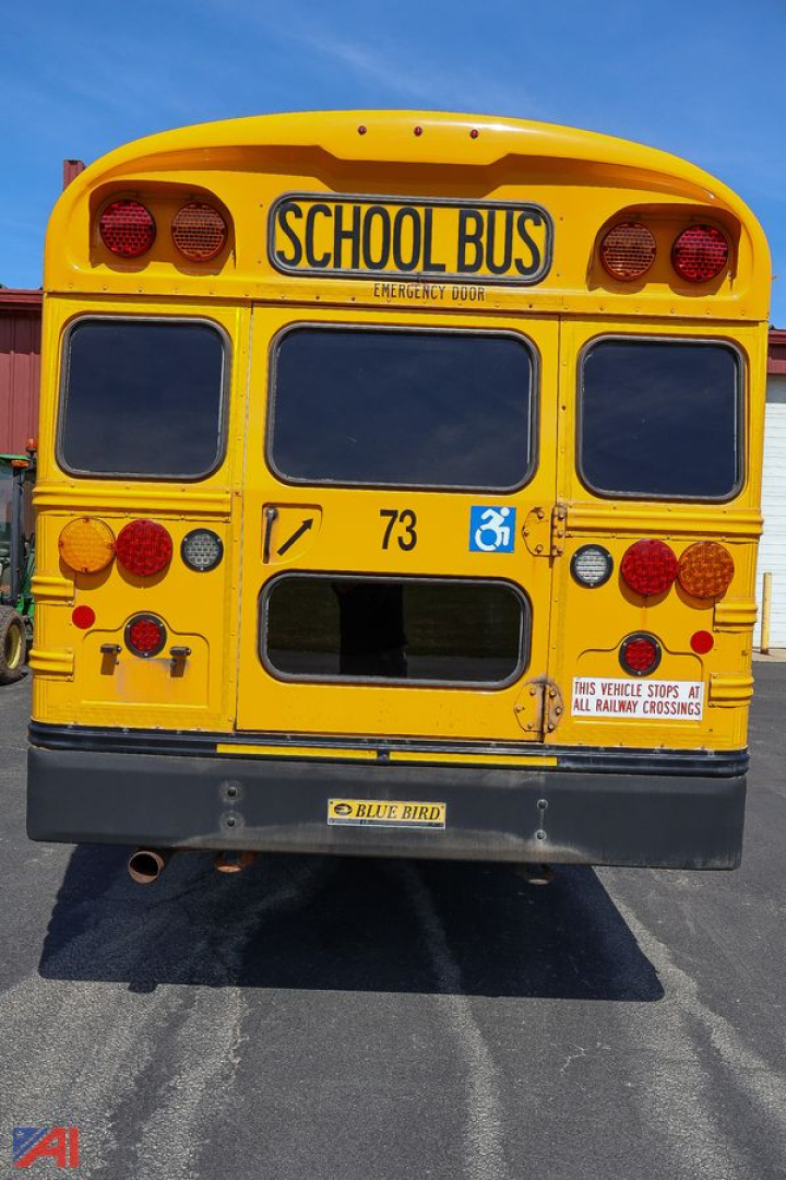 Yellow 2018 Blue Bird Vision school bus rear view showing large School Bus sign, dual round taillights, handicap symbol, and rear bumper.